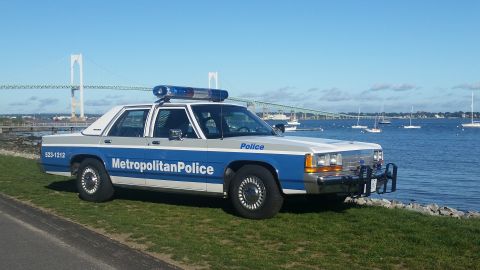 1991 Ford LTD Crown Victoria - A 1991 Ford Crown Victoria police car is parked near the water with a bridge in the background.