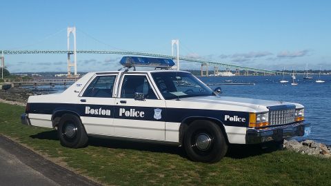 1991 Ford LTD Crown Victoria - A 1991 Ford Crown Victoria police car is parked by the water with a bridge in the background.