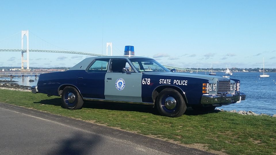Massachusetts State Police car parked by the water with a bridge in the background