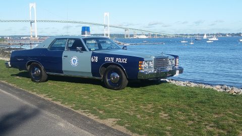 1991 Ford LTD Crown Victoria - This vintage Massachusetts State Police car is parked near the water, with a large bridge visible in the distance.
