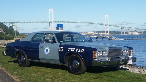 1991 Ford LTD Crown Victoria - Massachusetts State Police car, number 678, parked by the water with a bridge in the background.