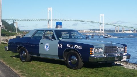 1991 Ford LTD Crown Victoria - A 1977 Ford LTD police car is parked by the water with a bridge in the background.