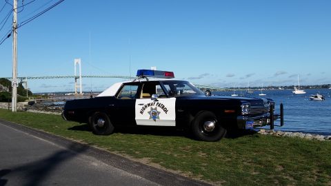 1991 Ford LTD Crown Victoria - This police car is parked by the water with a bridge and sailboats in the background.