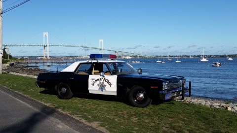 1991 Ford LTD Crown Victoria - A vintage police car with 'Highway Patrol' on the door sits by the water, a bridge visible in the distance.