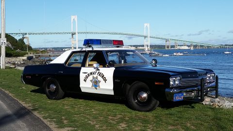1991 Ford LTD Crown Victoria - A vintage police car with 'HIGHWAY PATROL' text on its door sits by the water under a clear blue sky.