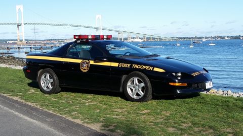 1991 Ford LTD Crown Victoria - A black police car, identified as a 1997 model, is parked by the water with a bridge in the background.