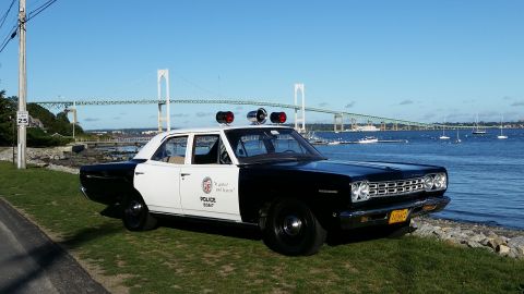1991 Ford LTD Crown Victoria - This 1968 Plymouth Belvedere police car is parked by the water with a bridge in the background.
