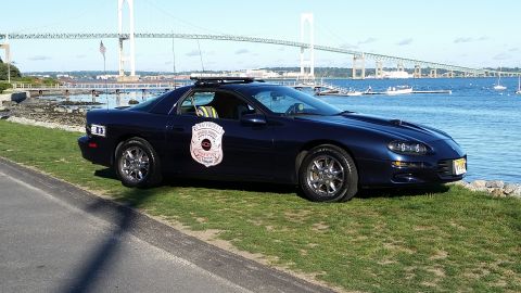 1991 Ford LTD Crown Victoria - Police car parked by the water with a bridge in the background.