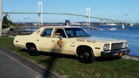 1991 Ford LTD Crown Victoria - A vintage police car, marked 'State Police', sits by the water with a large suspension bridge in the background.