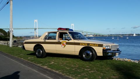 1991 Ford LTD Crown Victoria - This 1980s era state police car is parked by the water with a bridge in the distance.