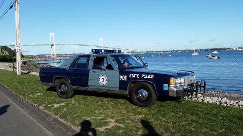 1991 Ford LTD Crown Victoria - A 1991 Ford Crown Victoria police car is parked by the water with a bridge visible in the distance.