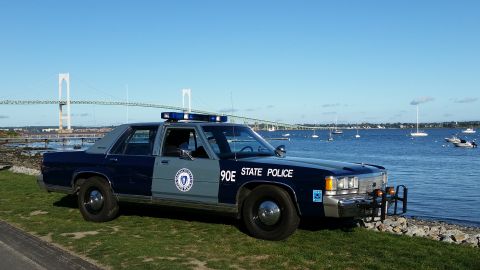 1991 Ford LTD Crown Victoria - A 1991 Ford Crown Victoria police car is parked near the water with a bridge in the distance.