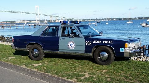 1991 Ford LTD Crown Victoria - A 1991 Ford Crown Victoria police car is parked by the water with a bridge in the background.