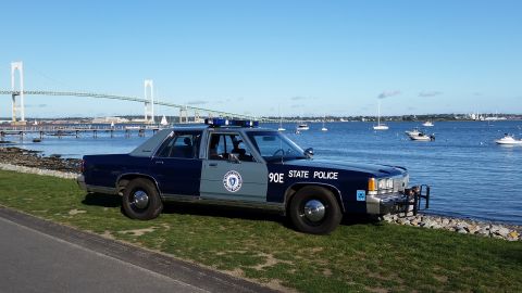 1991 Ford LTD Crown Victoria - Massachusetts State Police Crown Victoria parked near the water with a bridge and sailboats visible.