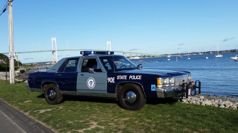 1991 Ford LTD Crown Victoria - This 1991 Ford Crown Victoria police car is parked by the water with a bridge in the distance.