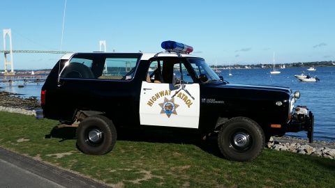 1991 Ford LTD Crown Victoria - A black and white Dodge Ramcharger SUV, marked as Highway Patrol, sits by the water under a clear blue sky.