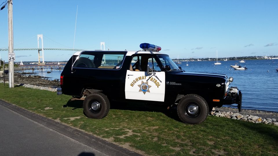 Black and white Dodge Ramcharger police vehicle with "HIGHWAY PATROL" text on the door, parked on grass by the water