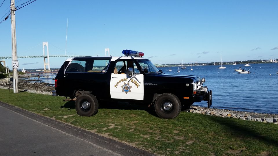 Black and white Dodge Ramcharger with "Highway Patrol" on the door parked by the water, bridge in background