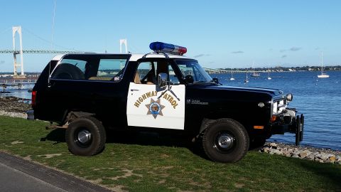 1991 Ford LTD Crown Victoria - This police SUV, likely from the 1980s, is parked near a body of water with a bridge in the background.