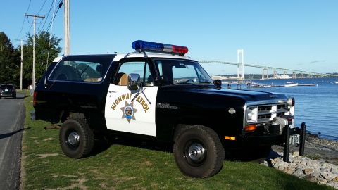 1991 Ford LTD Crown Victoria - This Dodge Ramcharger SUV is marked as "Highway Patrol" and is parked near a body of water with a bridge in the background.