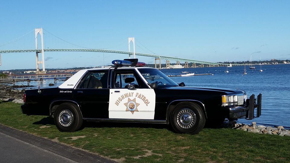 1991 Ford Crown Victoria police car parked by water with bridge in background