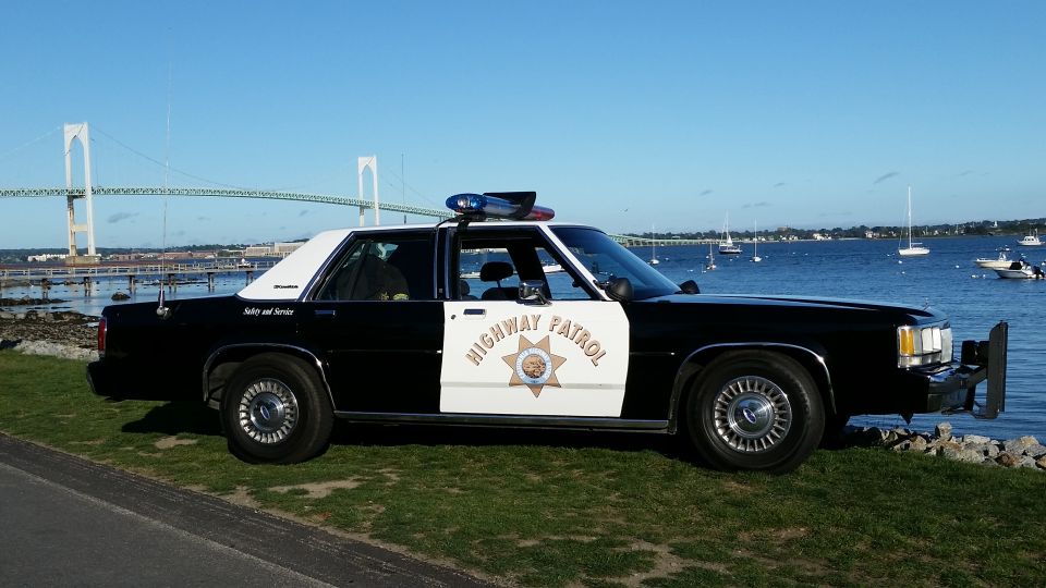 1991 Ford Crown Victoria Highway Patrol car parked by the water with a bridge in the background