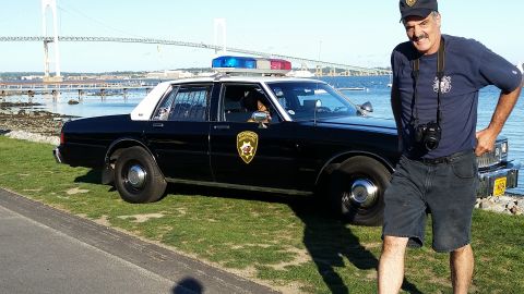 1991 Ford LTD Crown Victoria - A man stands next to a 1991 Ford Crown Victoria police car with a bridge in the background.
