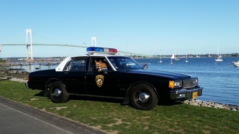 1991 Ford LTD Crown Victoria - Photo of a black and white Chevrolet Caprice police car parked by a bay near a suspension bridge, not a technical document.