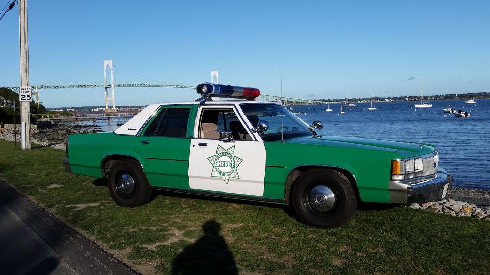 Green and white classic sheriff sedan with roof lights at a waterfront