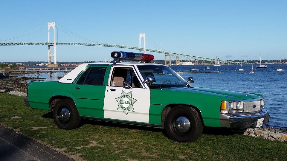 Green and white classic sheriff sedan with a star emblem by the water