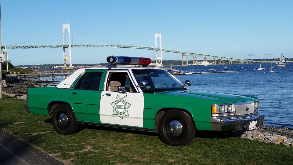 Green and white sheriff Crown Victoria police car beside a harbor