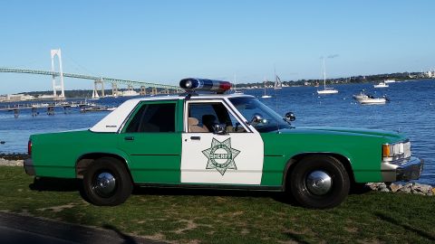 1991 Ford LTD Crown Victoria - Side-view photo of a green-and-white sheriff Ford LTD Crown Victoria police car parked along a bay.