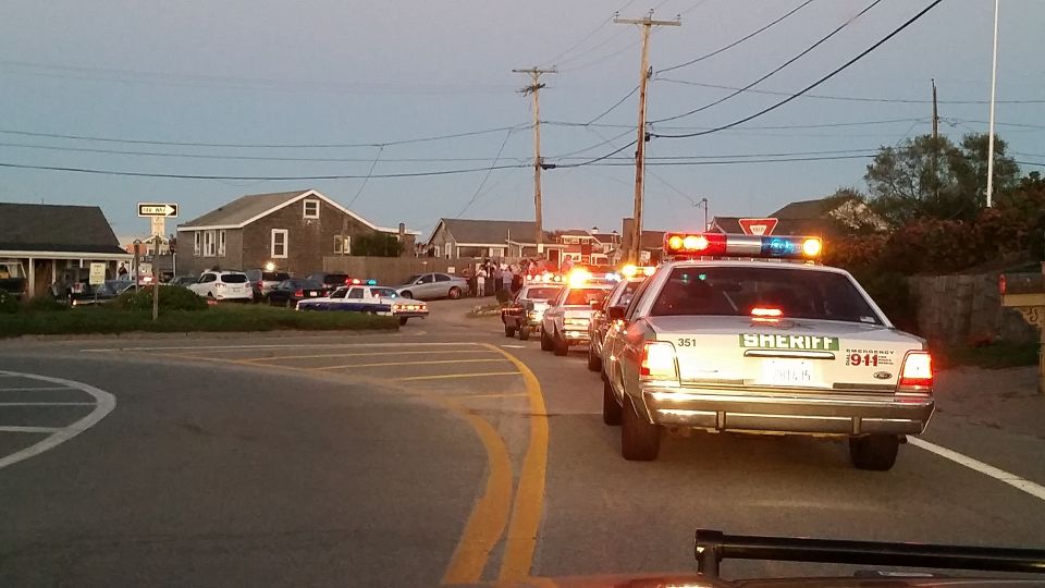 Police car procession on a coastal street at dusk