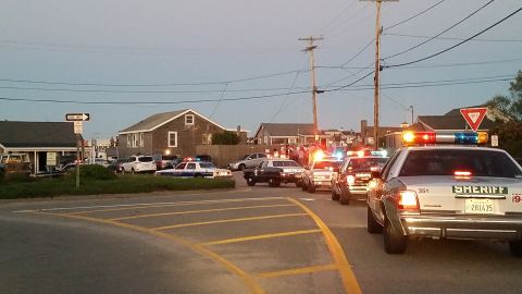 1991 Ford LTD Crown Victoria - Photo of several police cruisers with emergency lights, including a sheriff Crown Victoria, at a coastal intersection at dusk.