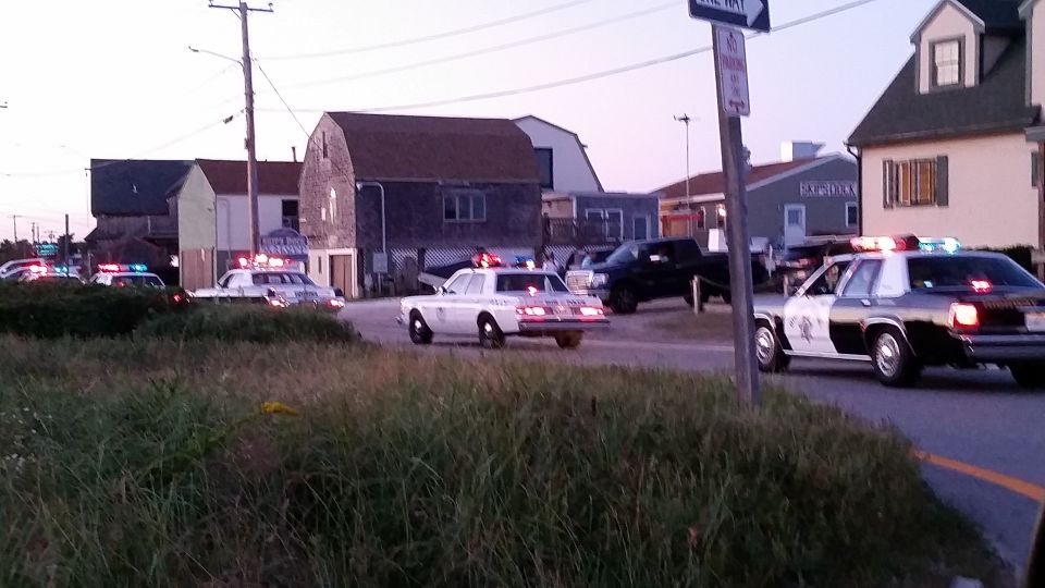 Multiple police cars with emergency lights at a coastal intersection at dusk