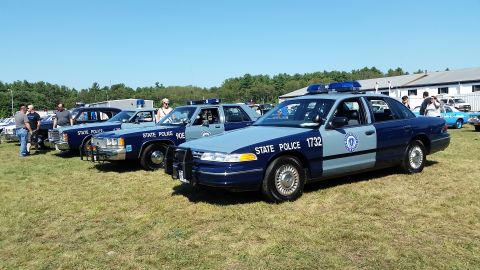 1991 Ford LTD Crown Victoria - Photo of a row of vintage Massachusetts State Police Ford Crown Victoria cruisers displayed on grass at a car show.