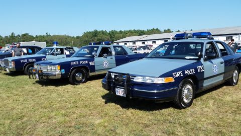 1991 Ford LTD Crown Victoria - Photo of a row of Massachusetts State Police Ford Crown Victoria cruisers on a grassy field at a car show.