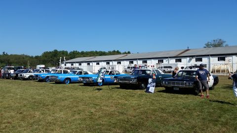 1991 Ford LTD Crown Victoria - A line of vintage police cars are parked on a grassy field in front of a long, white building under a clear blue sky. The cars are mostly s…