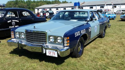 1991 Ford LTD Crown Victoria - A light blue and dark blue vintage police car, identified as "STATE POLICE 678" on the side, is parked on a grassy field in front of a buil…