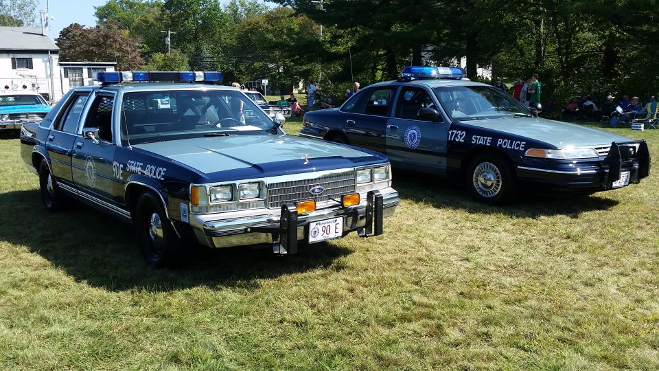 Two Ford Crown Victoria police cars parked on grass.