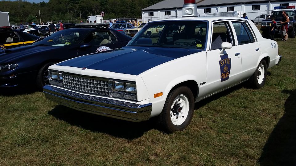 White and blue 1980s Pennsylvania State Police sedan with light bar.