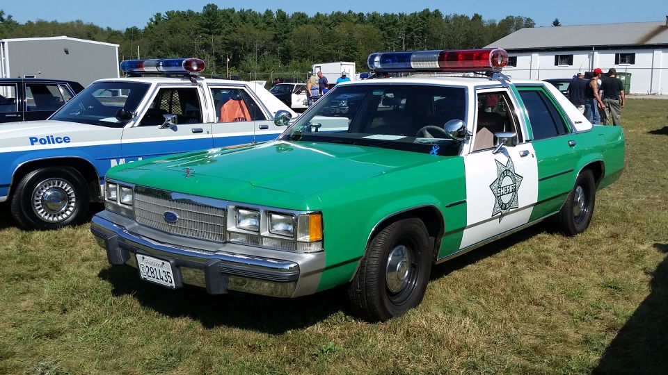 Green and white Ford Crown Victoria Sheriff's car with light bar.