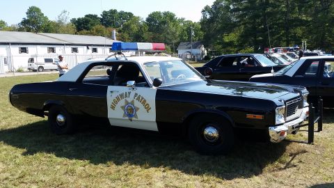1991 Ford LTD Crown Victoria - Photograph of a 1970s Dodge sedan painted in California Highway Patrol black-and-white livery, parked on grass at a show.
