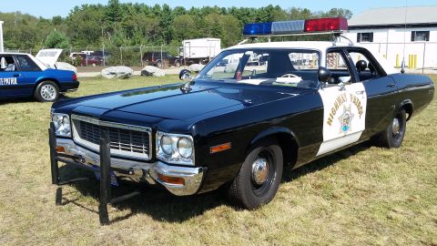 1991 Ford LTD Crown Victoria - Photograph of a 1970s Dodge sedan in California Highway Patrol livery with push bar and roof lights at an outdoor show.