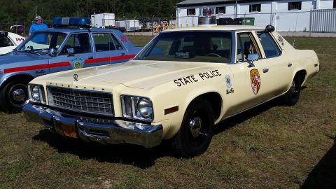 1991 Ford LTD Crown Victoria - A vintage Plymouth Gran Fury police car is displayed outdoors next to another police vehicle.