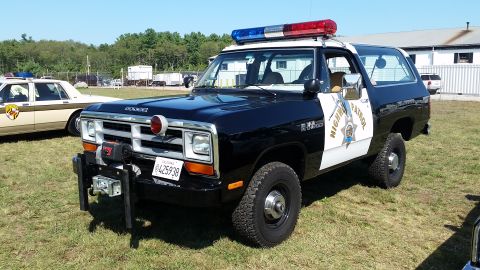 1991 Ford LTD Crown Victoria - A Dodge Ramcharger police SUV is parked on grass next to another police car.
