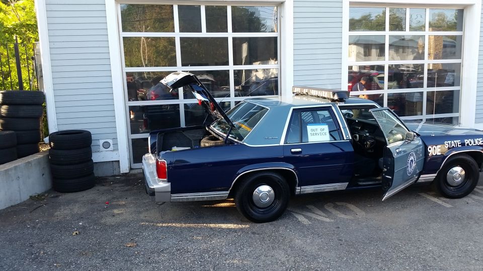 Blue state police Crown Victoria with open trunk and OUT OF SERVICE window sign