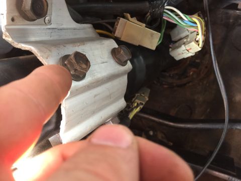 1986 Ford Bronco - A close-up view shows a vehicle's wiring harness and a metal mounting bracket secured with bolts.