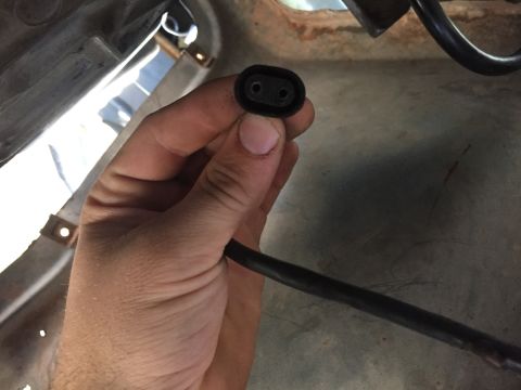 1986 Ford Bronco - Close-up of a hand holding a black electrical connector with two pins.
