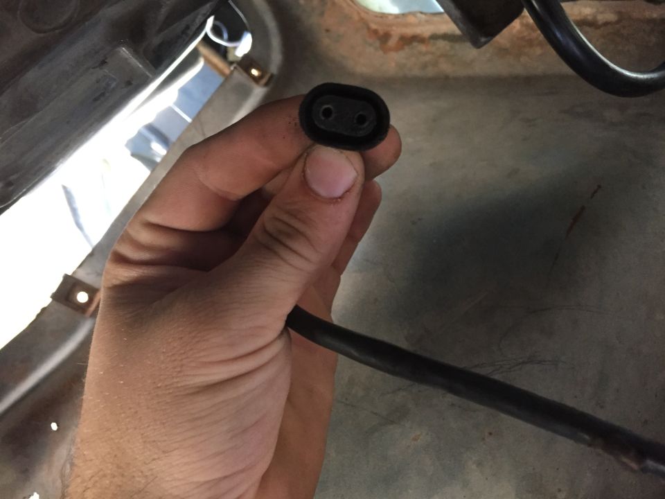 Hand holding a black electrical connector with two pins